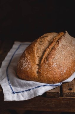 Taze sıcak çavdar ekmeği, beyaz keten peçetede koyu bir arka planda..