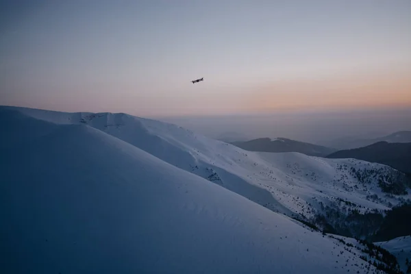 drone gün batımı arka planda kar kaplı tepeler üzerinde uçan 