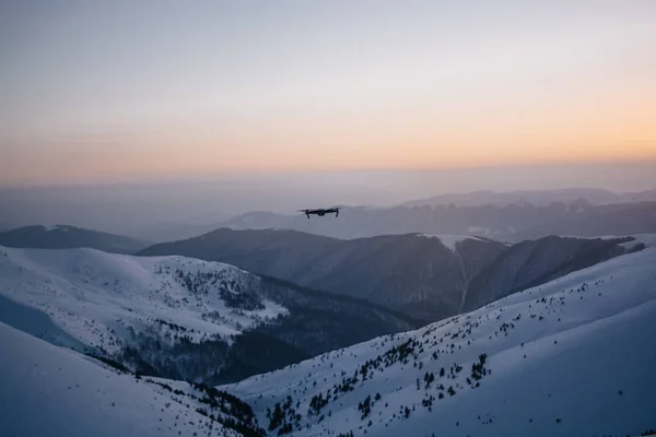 drone gün batımı arka planda kar kaplı tepeler üzerinde uçan 