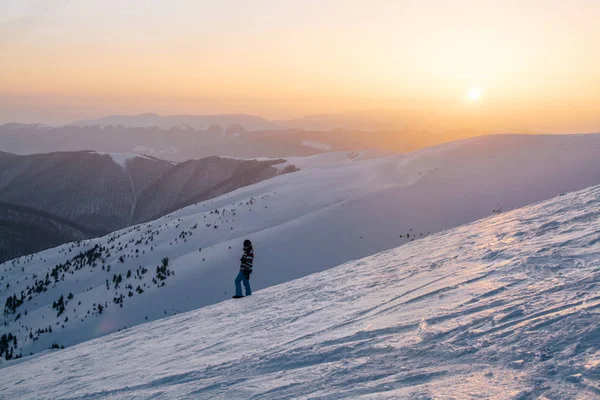 gün batımı sırasında karlı tepenin üzerinde duran kar yatılı silüeti