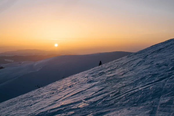 gün batımı sırasında karlı tepenin üzerinde duran kar yatılı silüeti