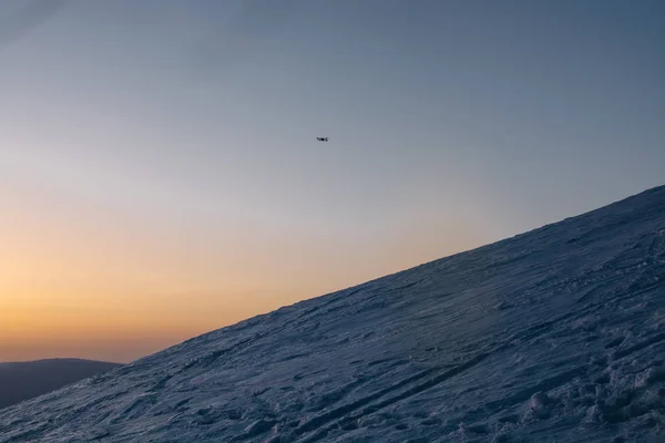 drone gün batımı arka planda kar kaplı tepeler üzerinde uçan 