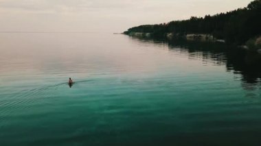 Günbatımı sırasında suda yürüyen kadın