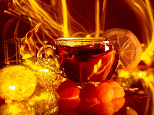 Vino caliente caliente caliente de Navidad en dos tazas blancas pequeñas con especias y cítricos sobre un fondo blanco con una guirnalda en el fondo — Foto de Stock