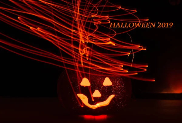 Calabaza de Halloween con cara de miedo sobre fondo negro. La inscripción Halloween 2019 —  Fotos de Stock