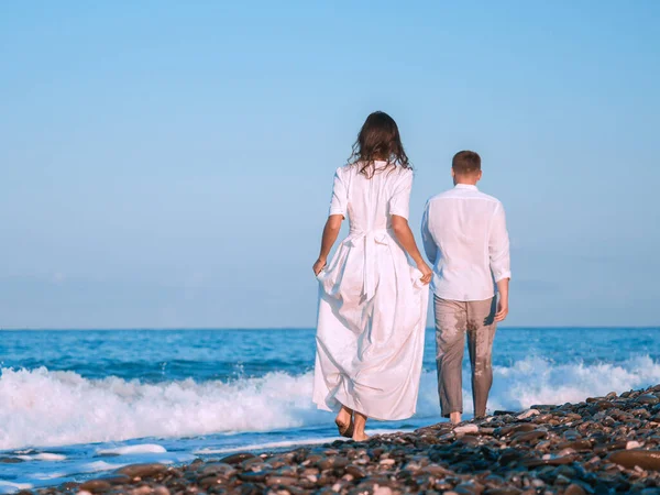 Birbirine aşık bir çift kumsalda beyaz elbiseler içinde koşuyor..