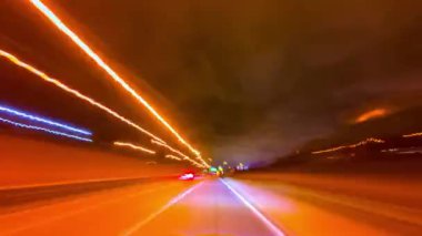 Gece şehirde hızlı bir araba yolculuğu sokak ışıklarının altında, uzun süre. Işıkların ve neon ışıkların yansıması, arabanın ön camında. Tema şehir ve gece hayatına hızlı bir şekilde taşınan otomobil.