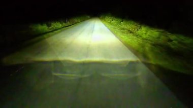 Şehir yolunda gece sürüşü. Karanlık bir gecede ormanın içinden sadece farlarla geçmek. Kırsal kesimde seyahat ederken. Kayalık bir off-road pistinde çakıllı toprak yolda ilerliyorum.