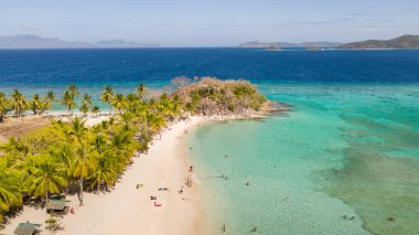 Beyaz bir plaja sahip lagün. Turistler plajda dinlenmek.