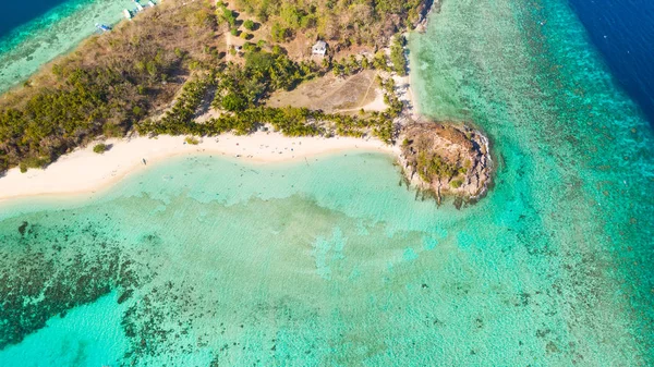 Ditaitayan adasında beyaz kumlu plaj. Adada tekneler ve turistler.