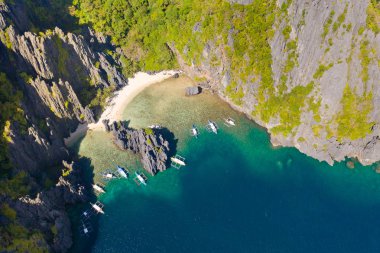 Kayalıklarla çevrili güzel bir lagün. Kayalıklarla çevrili küçük bir gizli tropikal lagün içinde yüzücülerin havadan drone görünümü