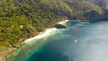Beyaz sahili olan kayalık sahil. Orman ile tropikal ada.