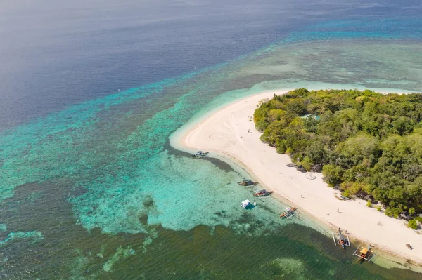 Uma pequena ilha rodeada por água azul e recifes de coral, uma vista superior . — Fotografia de Stock