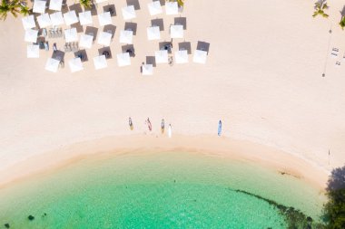 Beyaz plajda plaj şemsiyeleri ve şezlonglar.