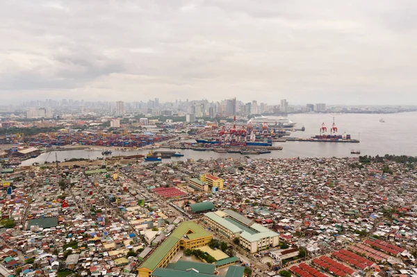 Puerto en Manila, Filipinas. Puerto marítimo con grúas de carga. Paisaje urbano con áreas pobres y centro de negocios en la distancia, vista desde arriba . — Foto de Stock