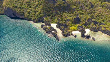 Kayalık kıyı ve beyaz plaj ile tropikal ada. Tekne ile turistik rotalar.