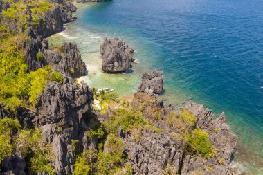 Beyaz sahili olan kayalık sahil. Orman ile tropikal ada.