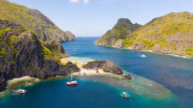 Beyaz sahili olan kayalık sahil. Orman ile tropikal ada.