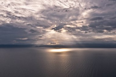 Denizin üzerinde bulutlar ve güneş ışınları. Güneş ışınları ve deniz üzerinde ağır bulutlar ile parlak ışık. Dramatik gökyüzü.