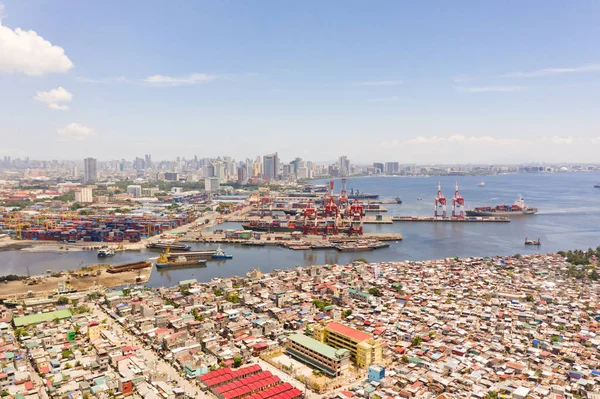 Porto em Manila, Filipinas. Porto marítimo com guindastes de carga. Cityscape com áreas pobres e centro de negócios à distância, vista de cima . — Fotografia de Stock