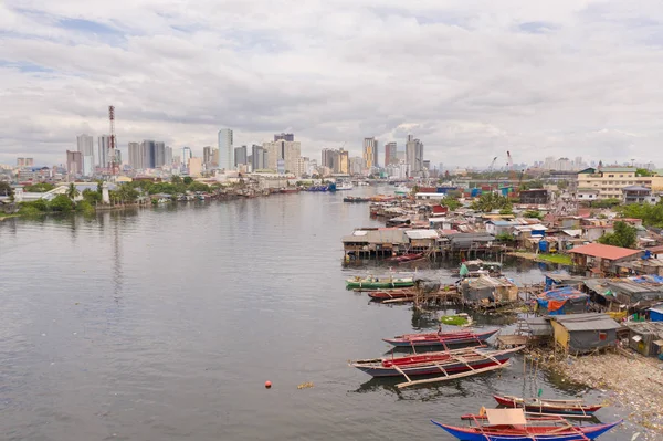 Manila slums on the background of a big city. Houses and boats of the poor inhabitants of Manila. Contrast social strata. — Stock Photo, Image