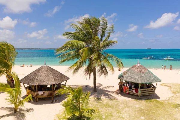 Ostrov DACO, Filipíny. Palmové stromy a bungalovy na bílé písečné pláži. Lidé odpočívejte na tropickém ostrově. — Stock fotografie