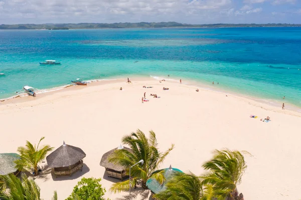 Daco adası, Filipinler. Palmiye ağaçları ve beyaz kumlu plajda bungalovlar. İnsanlar tropik bir adada rahatlarlar..