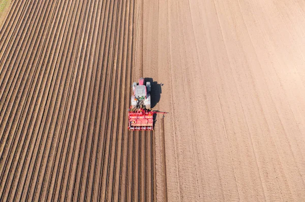 Tractor with disc harrows on farmland, top view. Tractor cuts furrows in a plowed field. Agricultural work with a tractor. — Stock Photo, Image