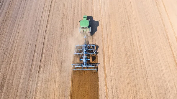 Трактор вирівнює поле, вид зверху. Сільськогосподарське поле готується до посадки овочів . — стокове фото