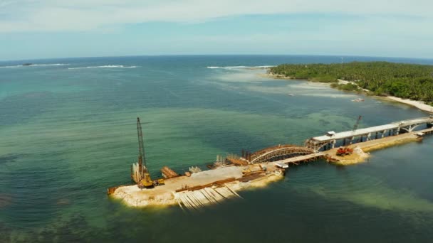 Строительство моста через залив. Строительная техника на мосту, вид сверху. Сиаргао, Филиппины . — стоковое видео