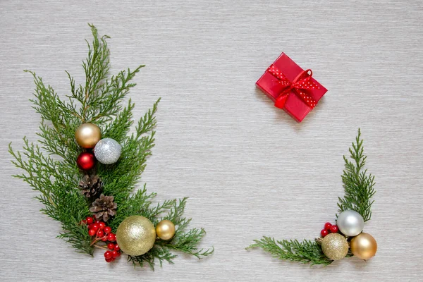 Décor de Noël sur fond clair. branches vertes et boules de Noël. Cadeau du Nouvel An dans une petite boîte rouge . — Photo