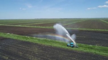 Tarım arazisindeki sulama sistemi. Alanı sulamak için büyük bir su akıntısı. Bir traktör tarlayı suluyor..