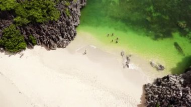 Turistler sahilde dinlenir. Caramoan Adaları, Camarines Sur, Matukad, Filipinler. Beyaz kumlu bir plajı olan tropik bir ada..
