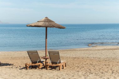 Şemsiye ve güneş boş kumsalda dinleniyor.