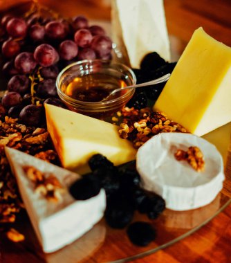 Farklı peynirler, üzüm, fındık, bal ekmek ve rustik ahşap arka plan üzerinde tarihler ile peynir tabağı