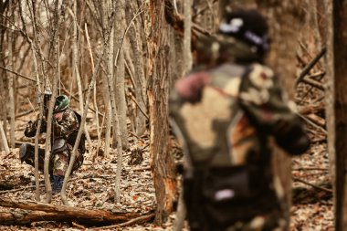 Koruyucu maskeli oyuncu paintball pusu pozisyonunda oynuyor