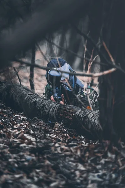 Koruyucu maskeli oyuncu paintball pusu pozisyonunda oynuyor