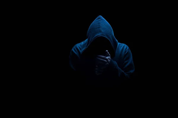 Man in black hood in the night darkness, dimly lit, concepts of danger crime terror