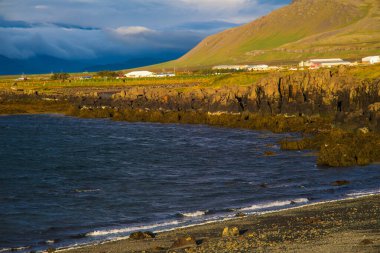 Gün batımında Köy ve Dağlarla Rocky İzlanda Sahil Çizgisi