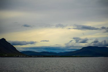 Karanlık çöktüğünde bulutlu gökyüzü olan kıyı manzarası