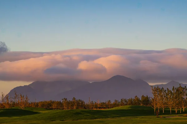 İzlanda 'da dağlarla ve bulutlarla gün batımı manzarası