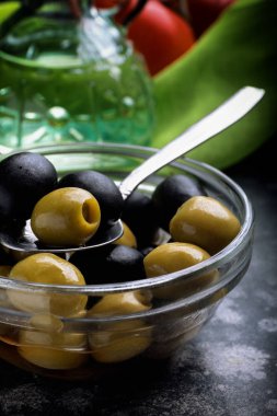 Yeşil ve siyah zeytin yağı şişe önünde siyah yüzey ıslak zeminde. Yakın çekim.