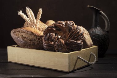 Birkaç loafs beyaz rustik ahşap kutusunda ekmek buğday koyu arka plan önünde kulaklı.