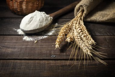 Demet buğday kulakları ve tahta kaşık un üzerinde ahşap rustik masa.