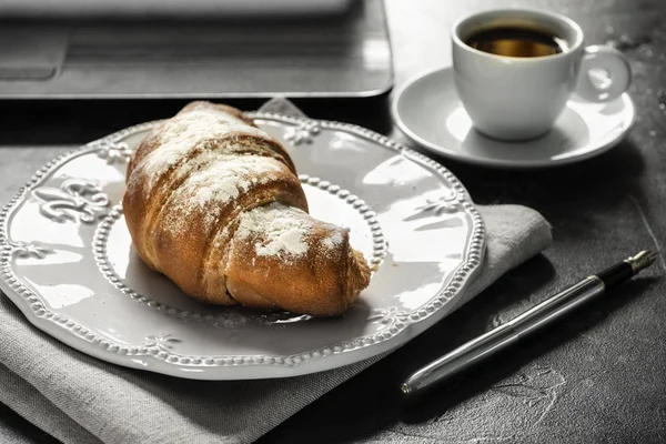 Rogalik z bliska na białym talerzu obok filiżankę kawy. Biuro styl z Notes i pióro. Lunch biznesowy w biurze. — Zdjęcie stockowe