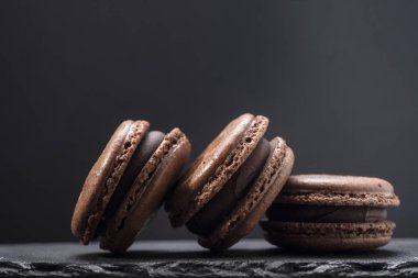 Koyu arka planda üç Çikolata macaroons yakın.