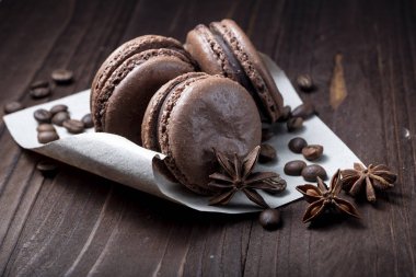 Üç çikolatalı makaron koyu ahşap masada yakın.