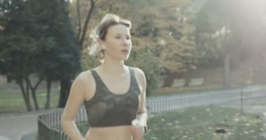 Parkta koşan koşucu kadın spor yapıyor, spor yapıyor, takip edilebilir teknoloji kullanıyor.