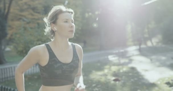 Sport meisje uitgevoerd In City Park dragen Smartwatch en draadloze oortelefoons — Stockvideo