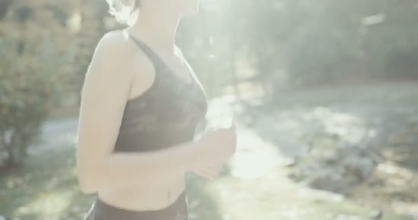 Kablosuz kulaklık içinde fitness kadın sabah ışığında çalışır — Stok video